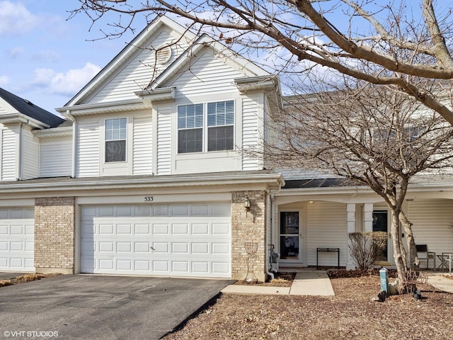 view of front of house featuring brick siding, covered porch, aphalt driveway, and a garage