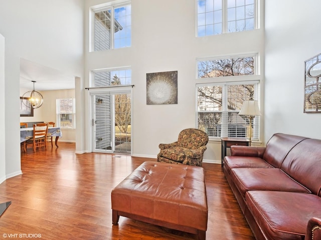 living area featuring baseboards, a notable chandelier, and wood finished floors