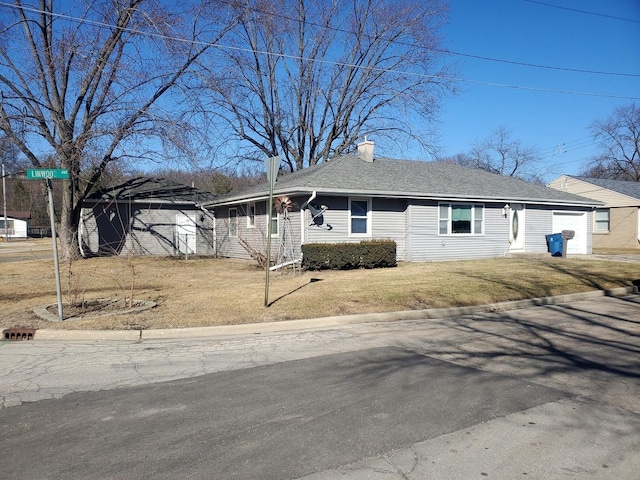 view of front of property with a garage, a front yard, roof with shingles, and a chimney