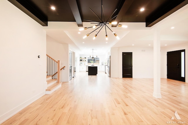 unfurnished living room with baseboards, light wood-style flooring, stairway, beamed ceiling, and a notable chandelier