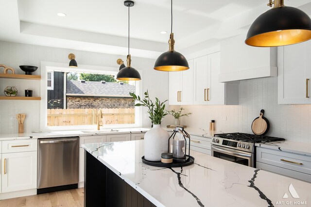 kitchen featuring light stone counters, stainless steel appliances, backsplash, white cabinets, and a sink