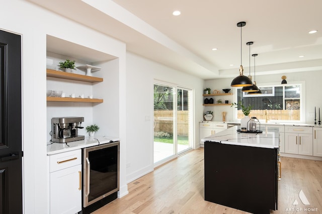 kitchen featuring wine cooler, a kitchen island, white cabinetry, light wood-style floors, and open shelves