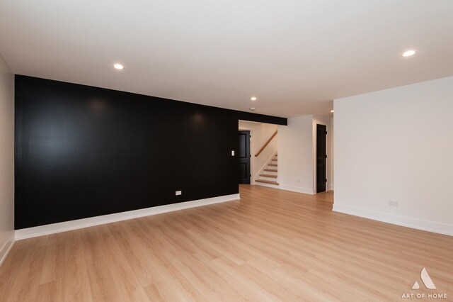 empty room with stairs, recessed lighting, light wood-type flooring, and baseboards