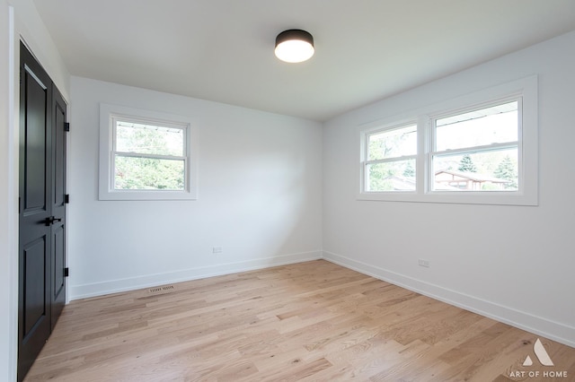 empty room featuring baseboards, visible vents, and light wood-style floors