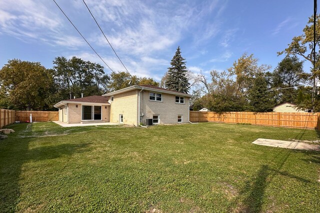 back of house with brick siding, a lawn, a patio area, and a fenced backyard