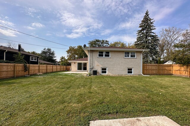 rear view of property with a fenced backyard, a lawn, and brick siding