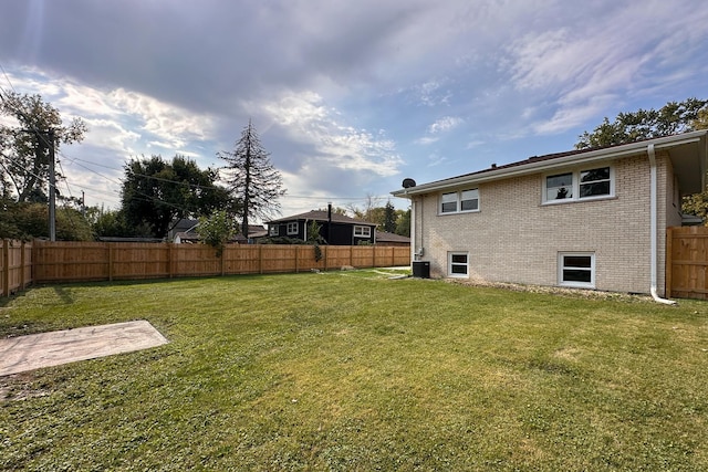 view of yard with central air condition unit and a fenced backyard