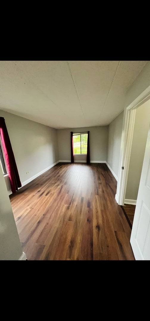 unfurnished room with wood finished floors and baseboards