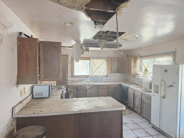 kitchen with white fridge with ice dispenser, light countertops, a sink, and a peninsula