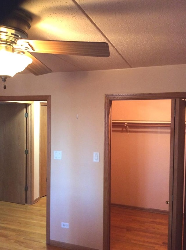 unfurnished bedroom with a textured ceiling, light wood-type flooring, a closet, and ceiling fan