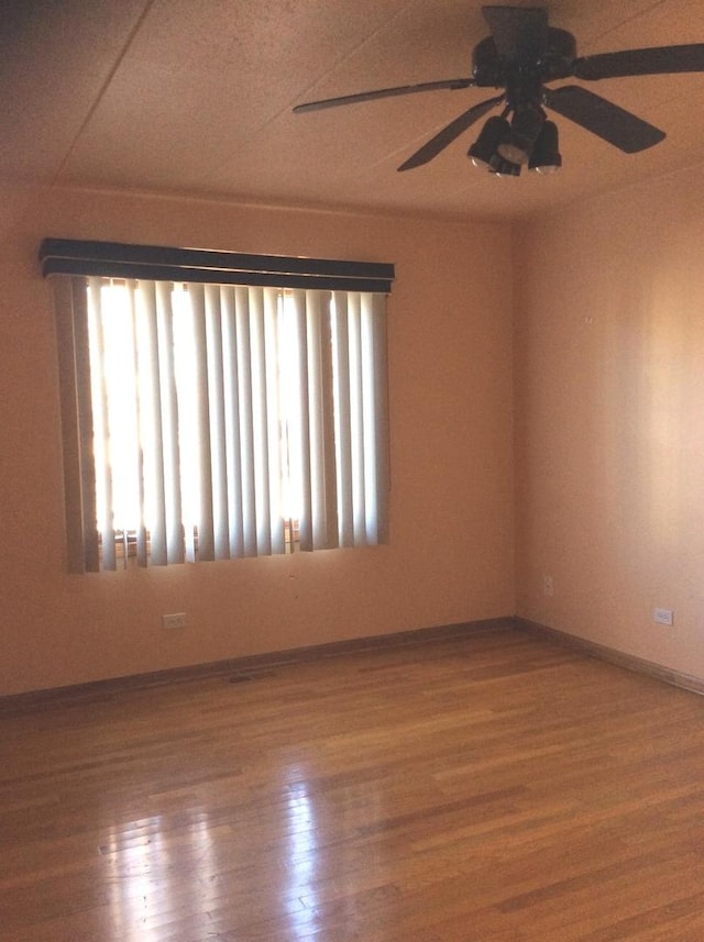 empty room featuring a ceiling fan, wood finished floors, and baseboards