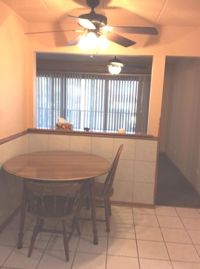 dining space with tile walls, light tile patterned floors, and a wainscoted wall