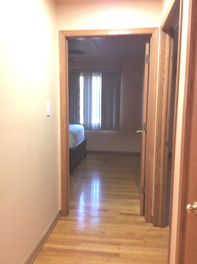 hallway featuring light wood-type flooring and baseboards