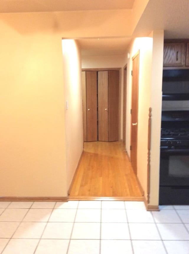 corridor with light tile patterned flooring and baseboards