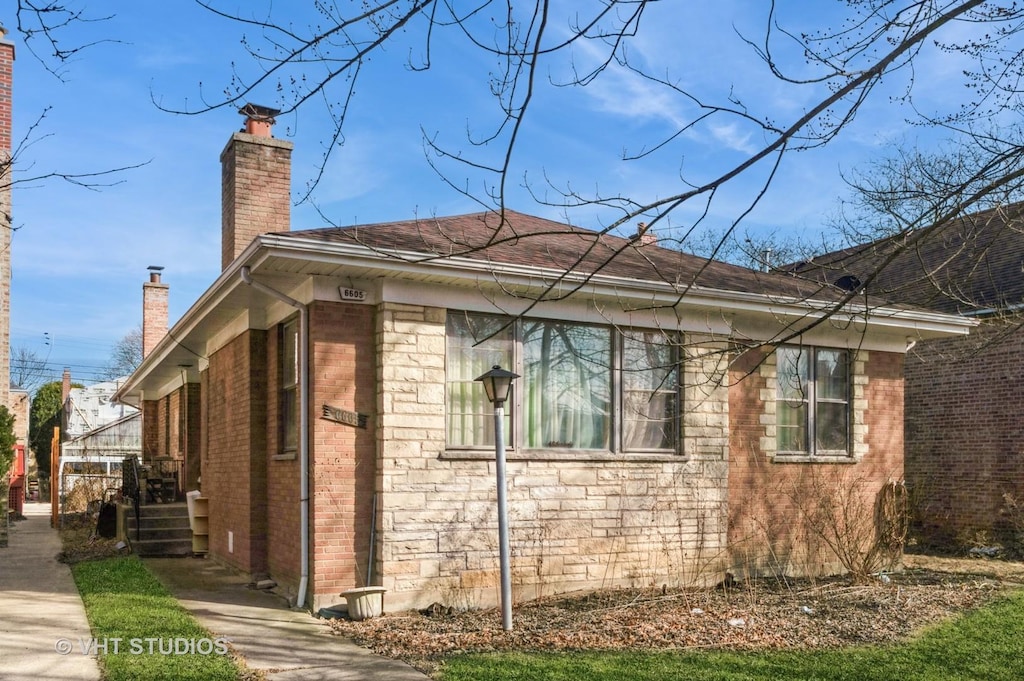 view of side of home featuring brick siding and a chimney