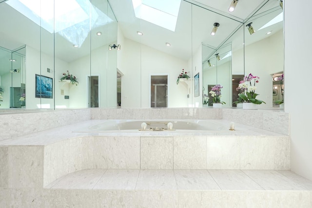 bathroom featuring a garden tub, a stall shower, and lofted ceiling with skylight