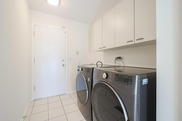 clothes washing area with light tile patterned floors, cabinet space, baseboards, and washer and clothes dryer