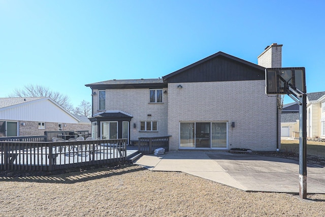 back of property featuring brick siding, a deck, a chimney, and a patio area