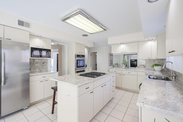 kitchen featuring a center island, light tile patterned floors, appliances with stainless steel finishes, and a sink