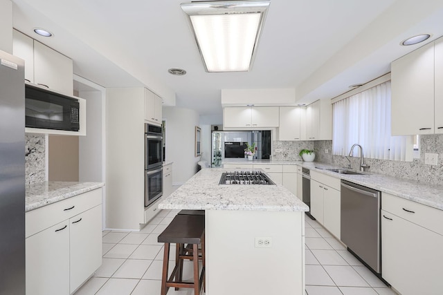 kitchen featuring tasteful backsplash, a breakfast bar area, light tile patterned floors, stainless steel appliances, and a sink