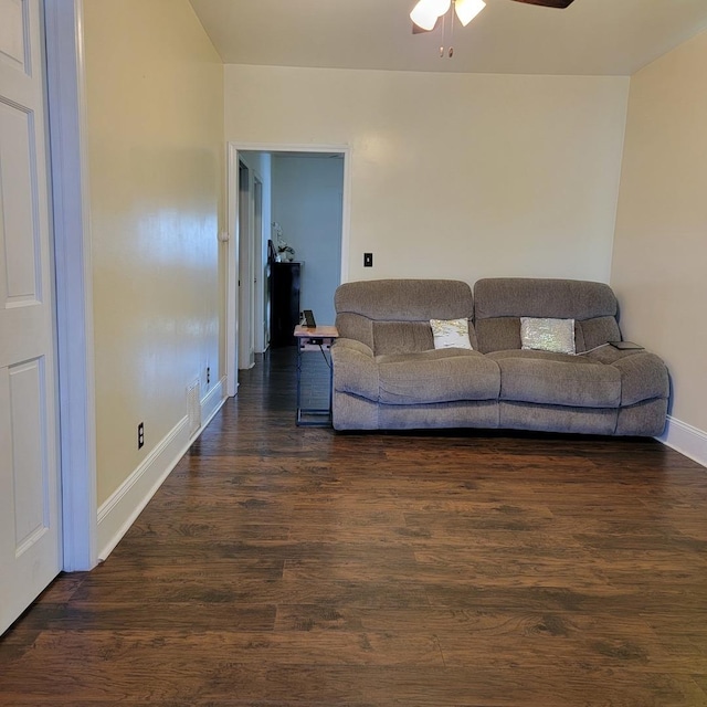 living area featuring baseboards, dark wood-type flooring, and ceiling fan