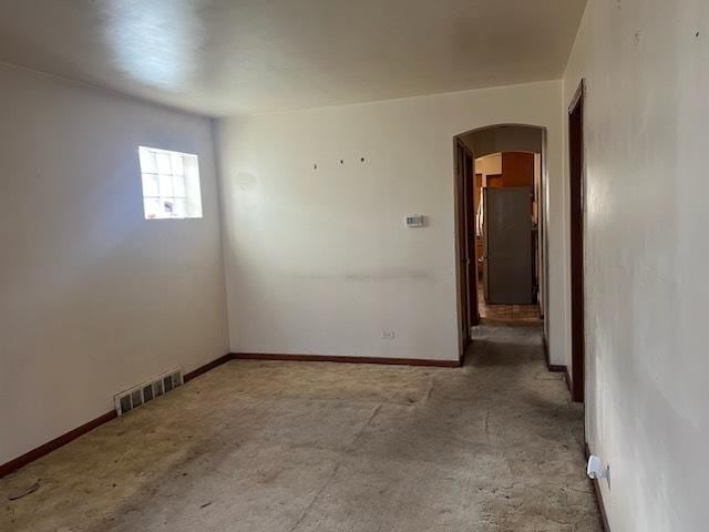 empty room with arched walkways, visible vents, and baseboards