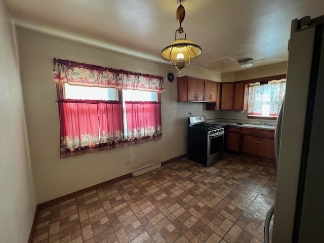 kitchen with baseboards, pendant lighting, light countertops, brown cabinets, and appliances with stainless steel finishes