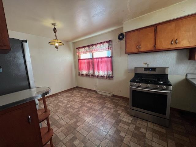 kitchen with pendant lighting, brown cabinetry, stainless steel gas stove, and baseboards