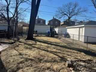 view of yard featuring a detached garage, an outbuilding, and fence