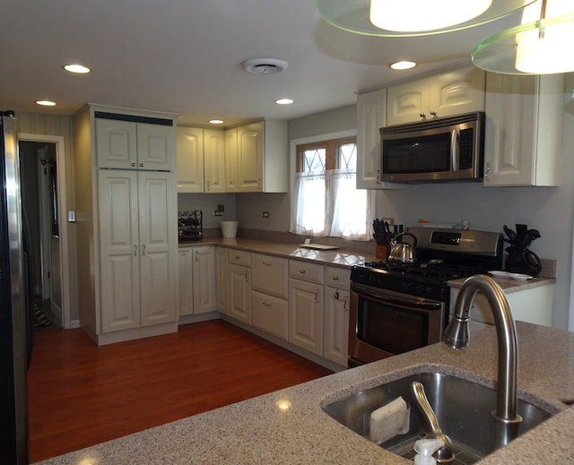kitchen with wood finished floors, light stone countertops, recessed lighting, a sink, and stainless steel appliances