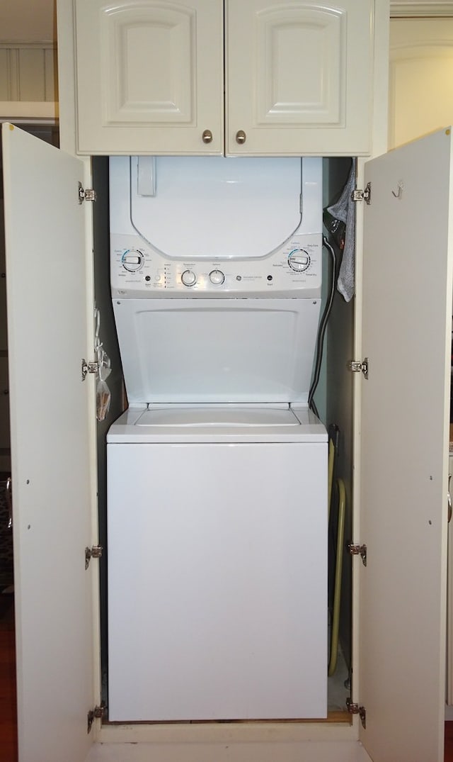 clothes washing area with cabinet space and stacked washing maching and dryer