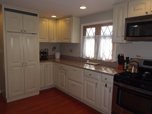 kitchen with white cabinetry, recessed lighting, wood finished floors, and appliances with stainless steel finishes