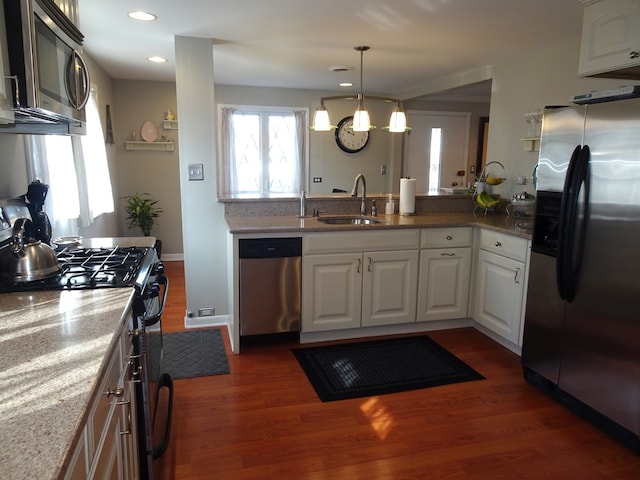 kitchen featuring light stone counters, dark wood-style flooring, appliances with stainless steel finishes, and a sink