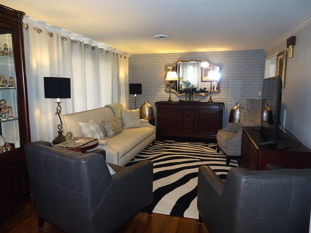 living room with wood finished floors, brick wall, and crown molding