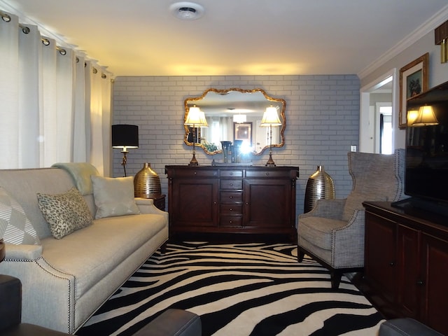 living area featuring visible vents, brick wall, and crown molding