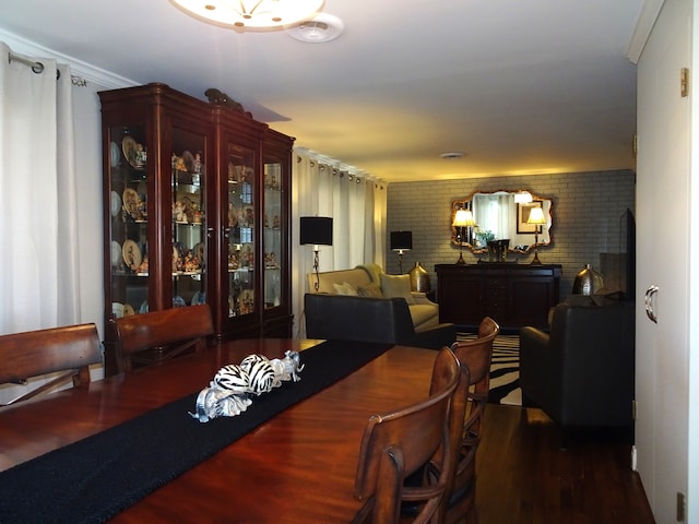 dining room with wood finished floors and brick wall