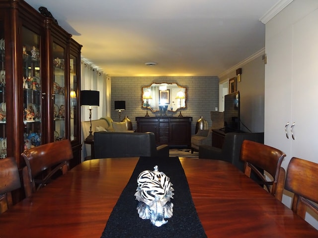 dining room featuring brick wall and ornamental molding