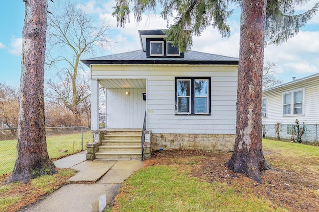 view of front of home featuring fence, a front lawn, and roof with shingles