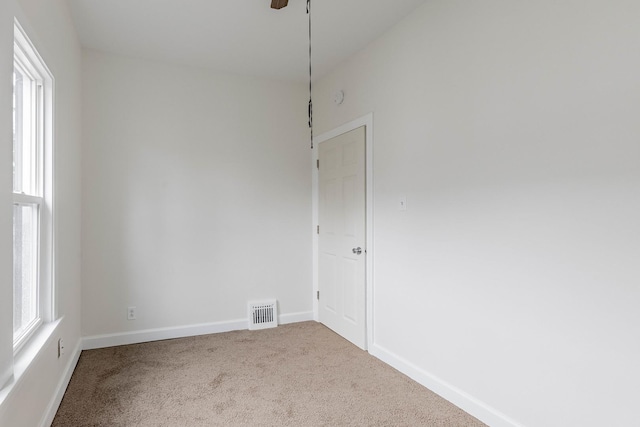 empty room with carpet, visible vents, plenty of natural light, and baseboards