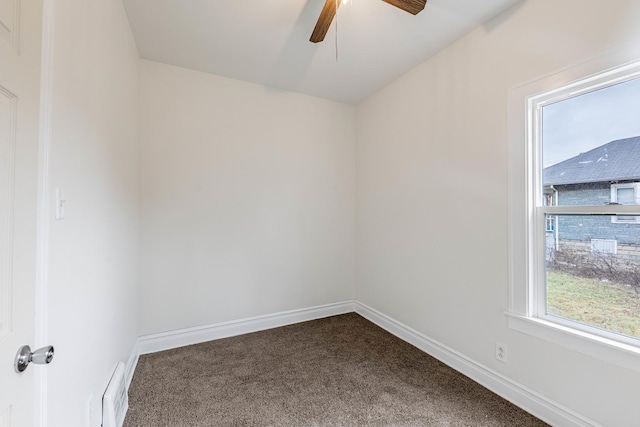 unfurnished room featuring a ceiling fan, visible vents, dark carpet, and baseboards