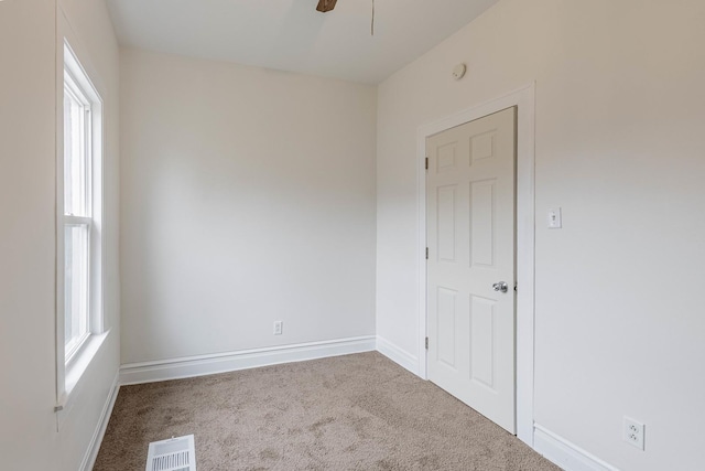 carpeted spare room with a ceiling fan, visible vents, and baseboards