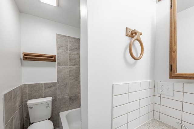 full bathroom with toilet, tile walls, and wainscoting