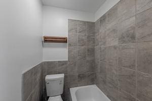 full bathroom with toilet and tile walls