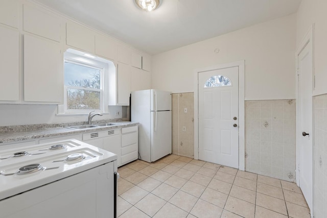 kitchen featuring tile walls, light countertops, electric range oven, freestanding refrigerator, and a sink