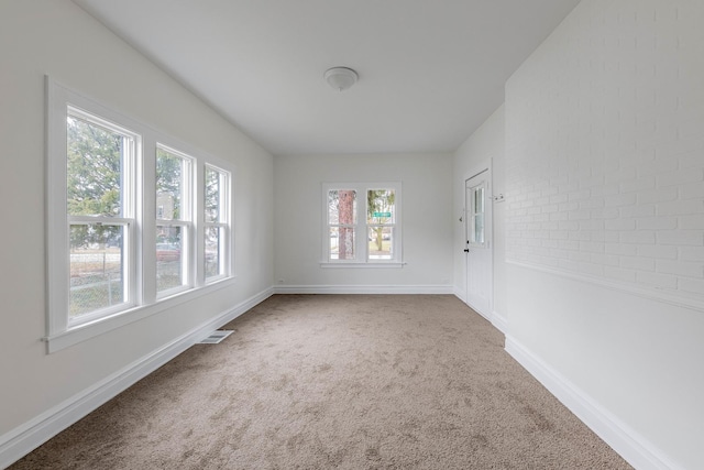 spare room featuring carpet, visible vents, and baseboards