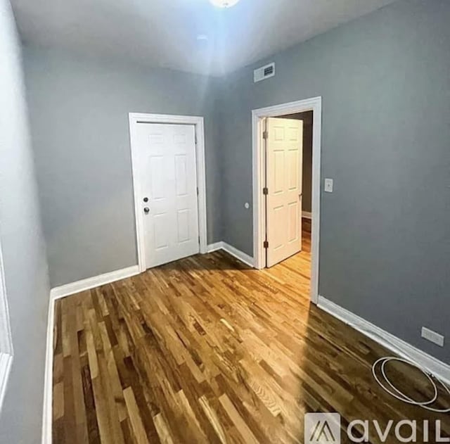 unfurnished room with baseboards, visible vents, and wood finished floors