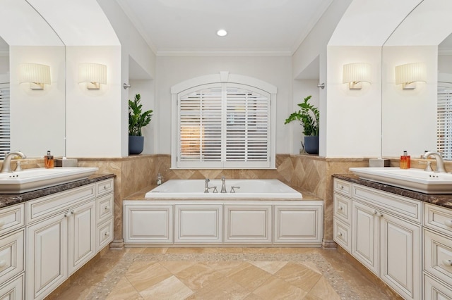 full bath with two vanities, a sink, tile walls, and crown molding