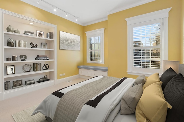 carpeted bedroom with baseboards, track lighting, and crown molding