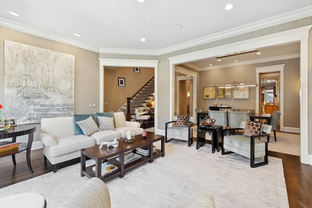 living room with recessed lighting, wood finished floors, baseboards, stairs, and ornamental molding