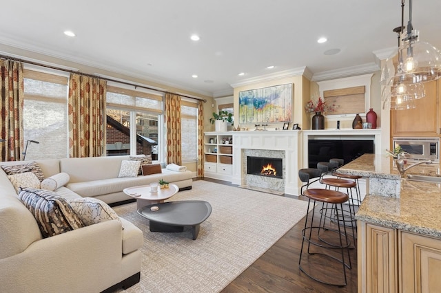 living area with dark wood-style floors, a fireplace, crown molding, and recessed lighting